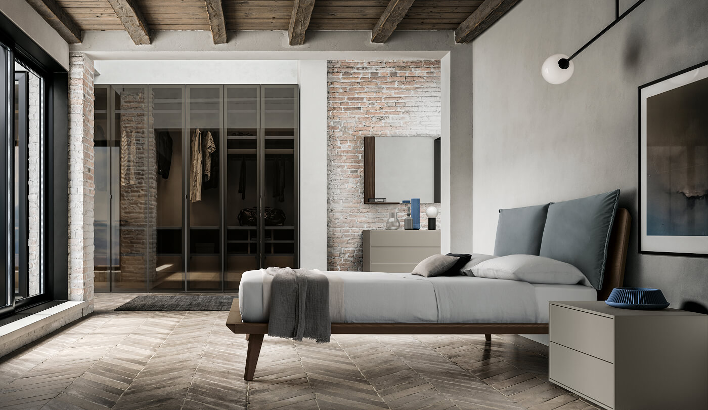 letto in legno con testiera di cuscini ampi grigi e armadio vetro fumè